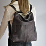 Image shows model wearing a distressed grey leather backpack.